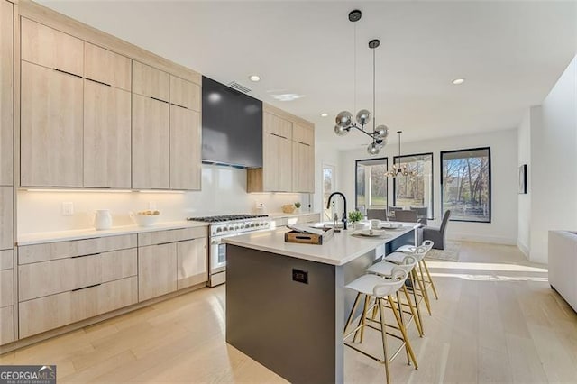 kitchen with range hood, light brown cabinets, stainless steel stove, a kitchen bar, and modern cabinets