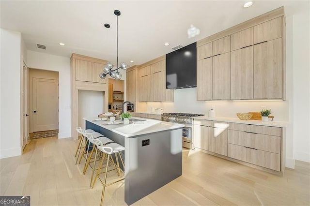 kitchen with high end stainless steel range, modern cabinets, a kitchen bar, and light brown cabinetry