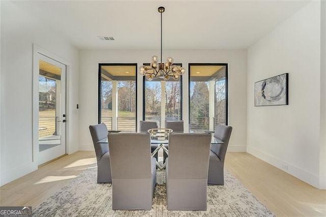 dining room featuring visible vents, baseboards, an inviting chandelier, and light wood-style flooring