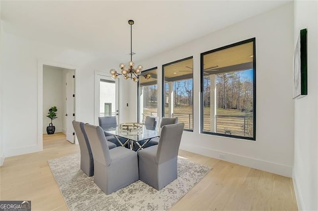 dining area featuring an inviting chandelier, light wood-style floors, baseboards, and a healthy amount of sunlight