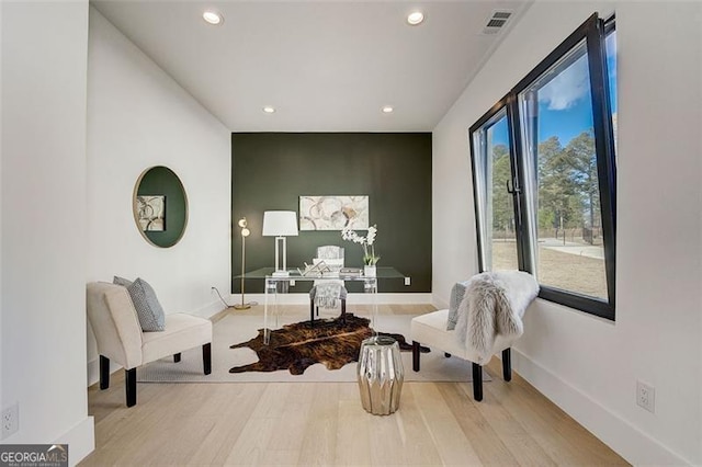 living area with wood finished floors, visible vents, and baseboards