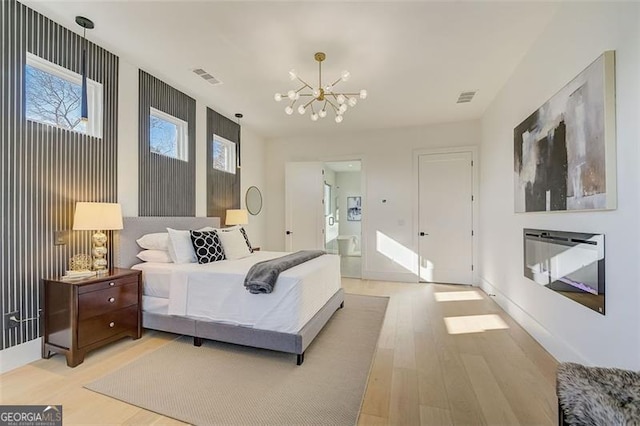 bedroom featuring a notable chandelier, visible vents, light wood-type flooring, and baseboards