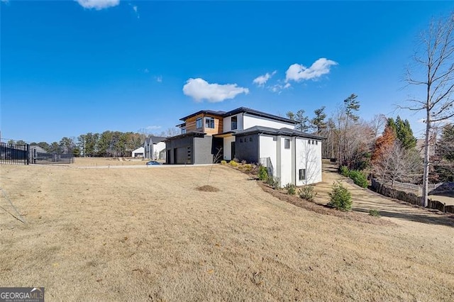 exterior space with an attached garage, fence, a lawn, and stucco siding