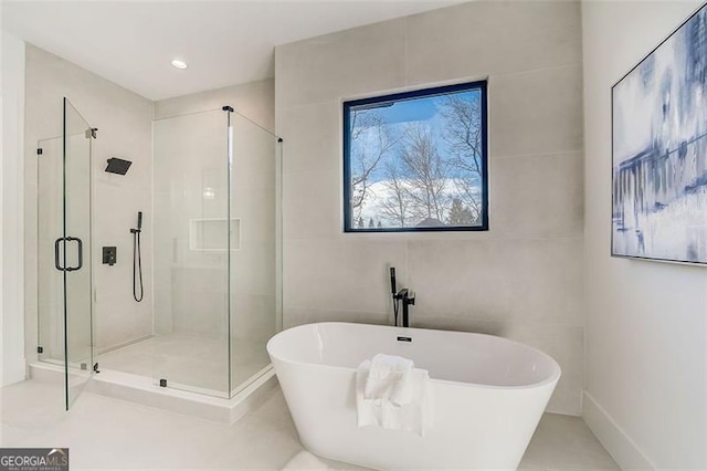 full bath featuring a shower stall, tile walls, and a freestanding tub