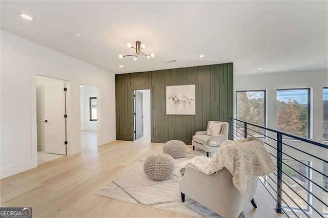 sitting room with recessed lighting, wood walls, light wood finished floors, and a chandelier