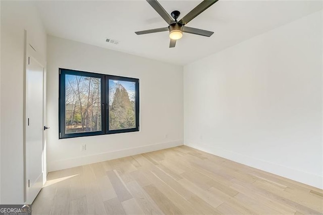 spare room featuring light wood finished floors, visible vents, baseboards, and a ceiling fan