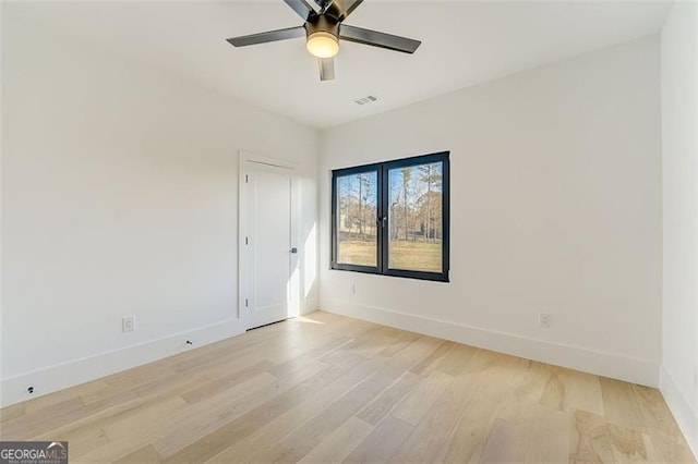 empty room with a ceiling fan, light wood-style floors, visible vents, and baseboards