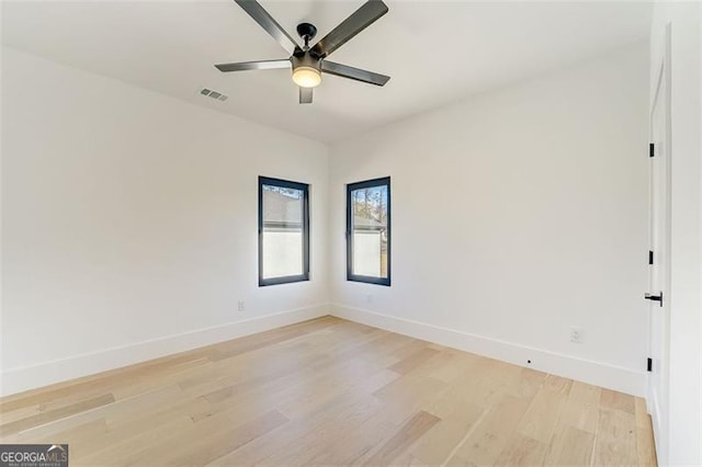 unfurnished room featuring light wood finished floors, visible vents, baseboards, and a ceiling fan