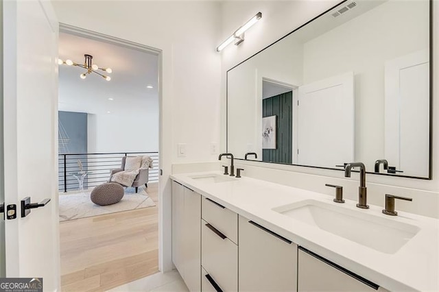 full bathroom featuring a sink, visible vents, wood finished floors, and double vanity