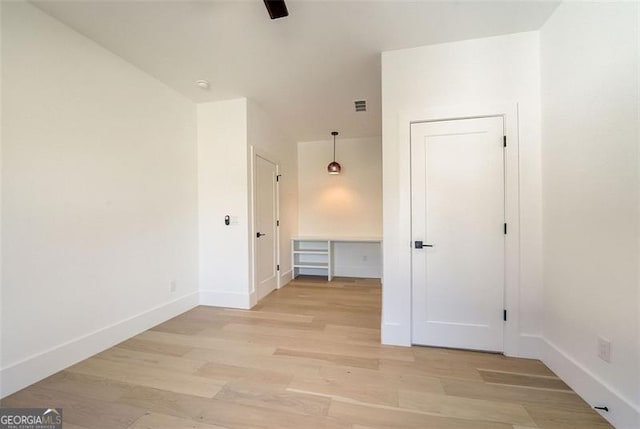 unfurnished room featuring light wood finished floors, visible vents, a ceiling fan, and baseboards