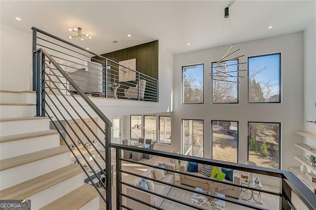 stairway featuring recessed lighting, a notable chandelier, and a towering ceiling