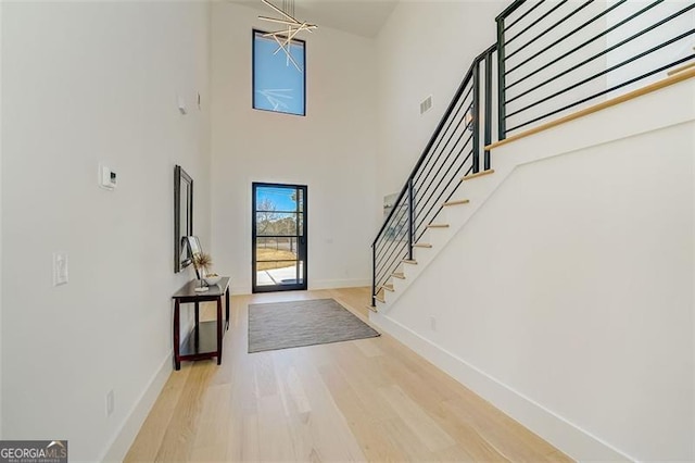 foyer featuring visible vents, a notable chandelier, wood finished floors, baseboards, and stairs