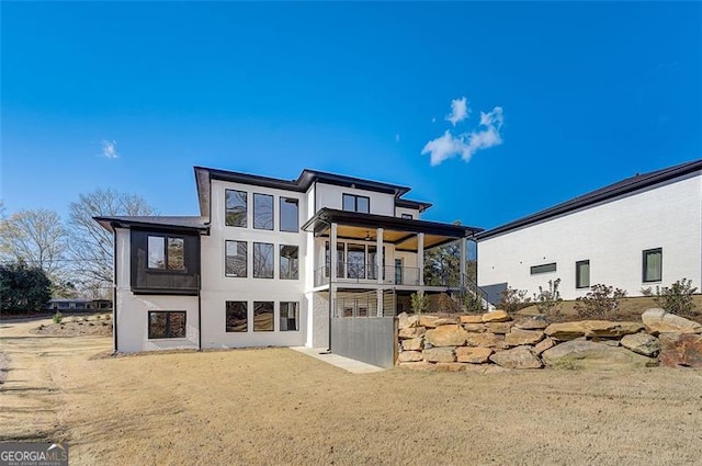 rear view of house with a balcony and stucco siding