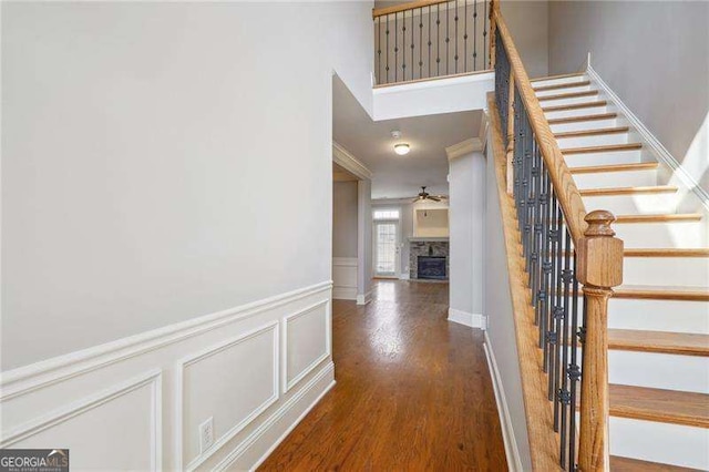 interior space with ceiling fan, stairway, a fireplace, wood finished floors, and a decorative wall