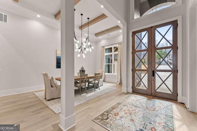 entrance foyer featuring beam ceiling, french doors, an inviting chandelier, light wood finished floors, and baseboards