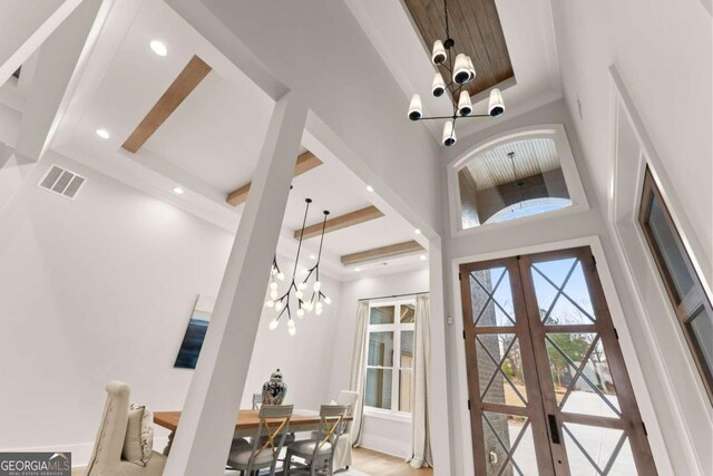 interior space featuring visible vents, beam ceiling, recessed lighting, french doors, and an inviting chandelier