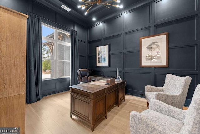 office space with a decorative wall, visible vents, and light wood finished floors