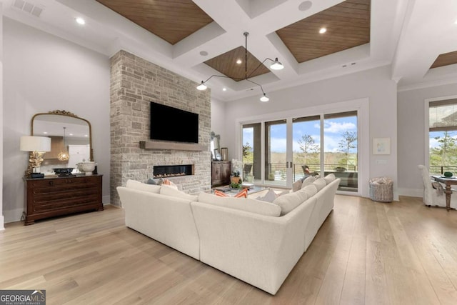 living area with visible vents, a fireplace, light wood-style floors, a towering ceiling, and coffered ceiling