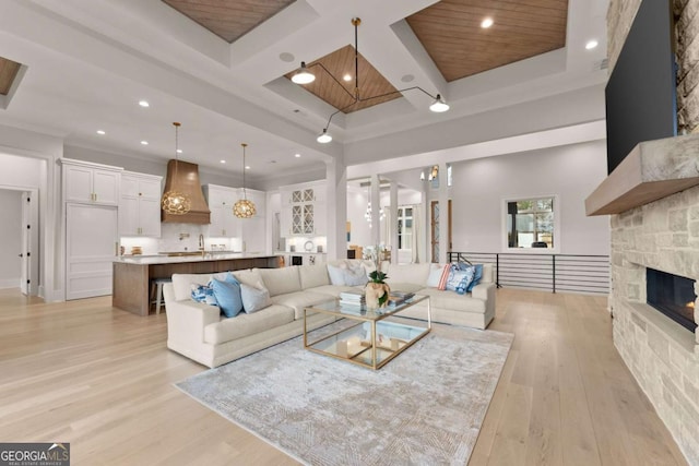 living area with beam ceiling, light wood-style flooring, coffered ceiling, recessed lighting, and a towering ceiling