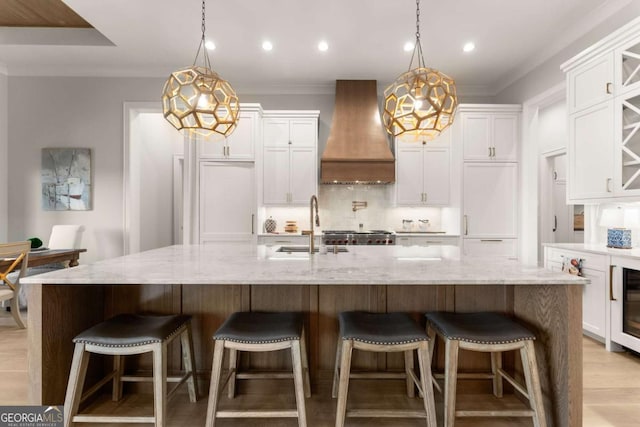 kitchen with crown molding, wall chimney range hood, backsplash, and a sink