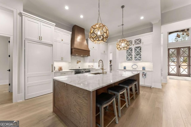 kitchen with stove, custom range hood, ornamental molding, and a sink