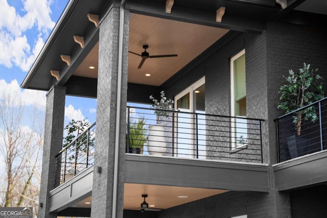 view of side of property featuring a balcony, brick siding, and ceiling fan