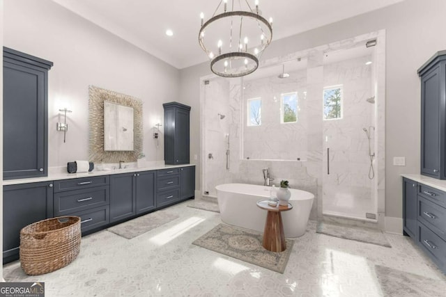 bathroom featuring a marble finish shower, a freestanding bath, a chandelier, and vanity