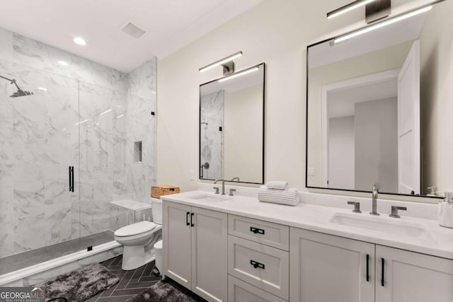 bathroom with double vanity, toilet, a marble finish shower, and a sink