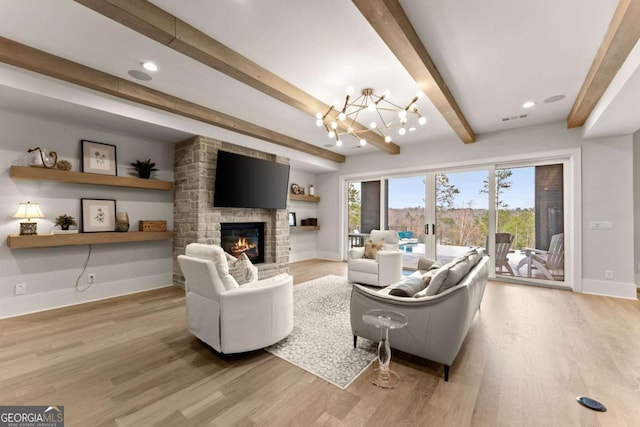 living room with a notable chandelier, wood finished floors, visible vents, and baseboards