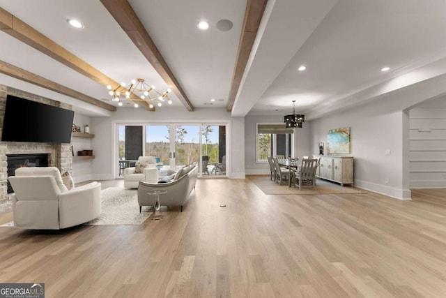 living room with beamed ceiling, light wood-style floors, an inviting chandelier, and a fireplace