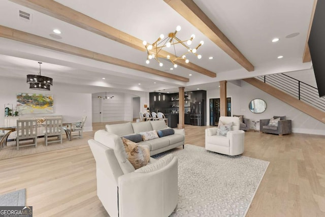 living area featuring light wood-type flooring, a notable chandelier, beamed ceiling, and visible vents