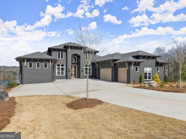 prairie-style home featuring concrete driveway, a garage, and a shingled roof