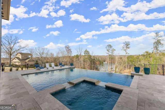 view of swimming pool featuring a patio area, a pool with connected hot tub, and fence