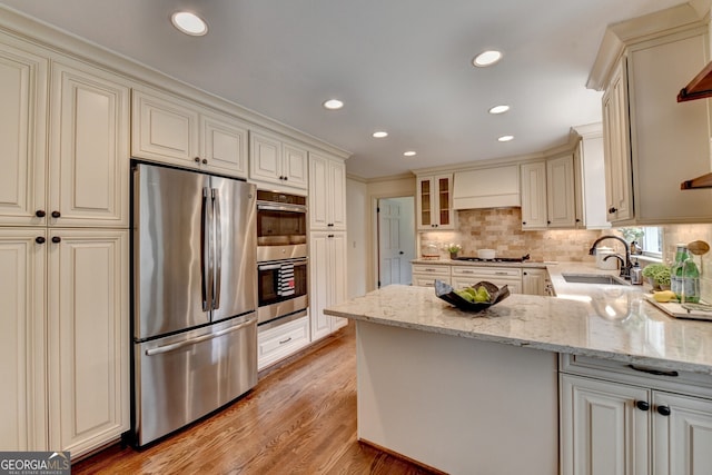 kitchen featuring a sink, cream cabinets, light stone countertops, and stainless steel appliances