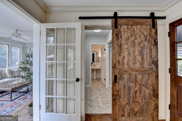 interior space with tile patterned flooring, ceiling fan, and a barn door