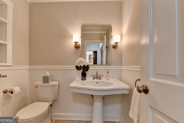 bathroom featuring toilet and a wainscoted wall