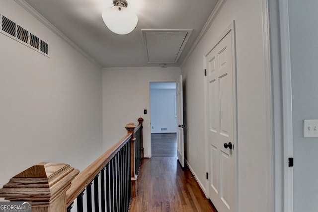 hallway with dark wood-style floors, visible vents, attic access, ornamental molding, and an upstairs landing