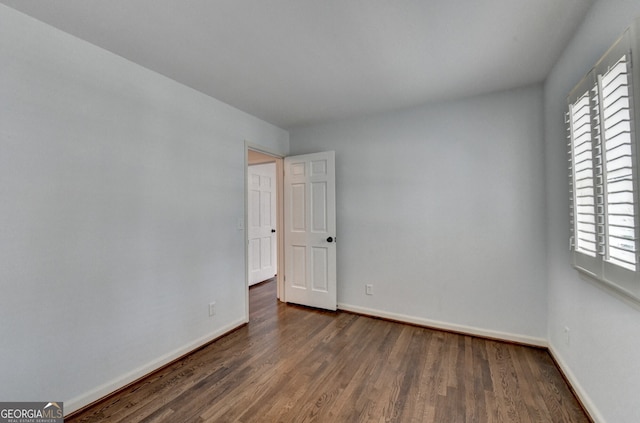 unfurnished room with dark wood-type flooring and baseboards