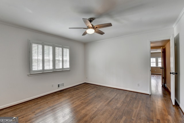 empty room featuring crown molding, visible vents, dark wood-style flooring, and ceiling fan