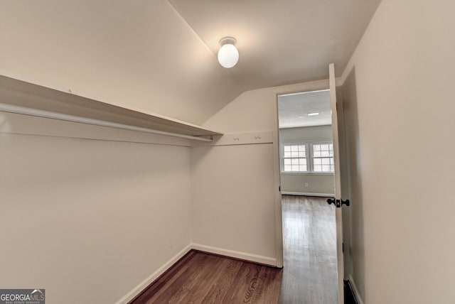 walk in closet with dark wood-style flooring and vaulted ceiling