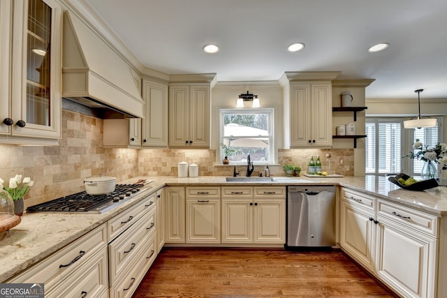 kitchen featuring cream cabinetry, a sink, stainless steel appliances, a peninsula, and custom exhaust hood