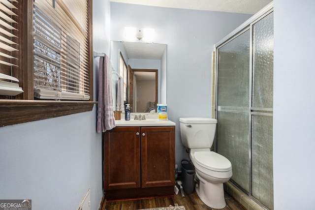 full bathroom featuring a stall shower, toilet, wood finished floors, and vanity