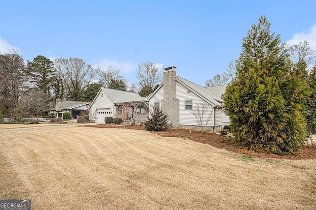 view of home's exterior featuring an attached garage, a yard, and a chimney