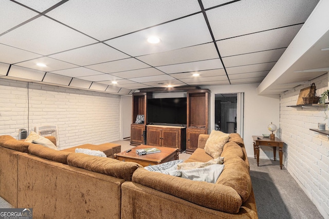 carpeted living room featuring a drop ceiling, recessed lighting, and brick wall