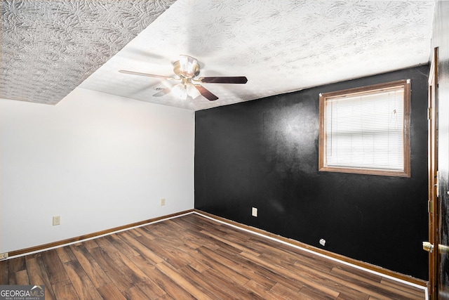 spare room with a textured ceiling, wood finished floors, baseboards, and ceiling fan