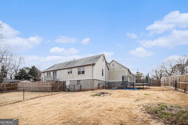 back of house featuring a trampoline and a fenced backyard