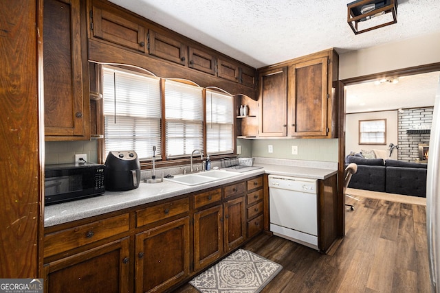 kitchen with dark wood-type flooring, a sink, a textured ceiling, white dishwasher, and light countertops