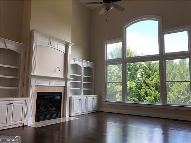 2741 Willowstone Dr, Duluth, GA 30096 - unfurnished living room featuring a tiled fireplace, a ceiling fan, a towering ceiling, and wood finished floors