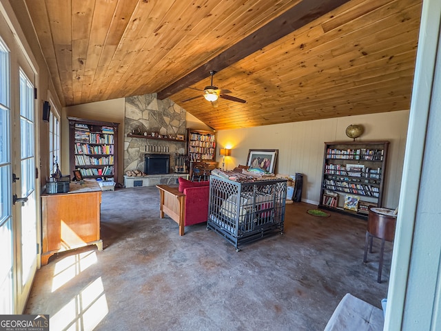 living area featuring vaulted ceiling with beams, concrete floors, a stone fireplace, wooden ceiling, and a ceiling fan