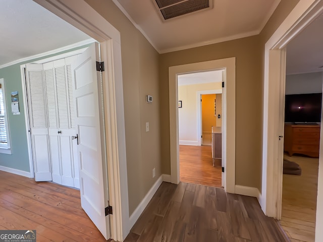 hallway with visible vents, crown molding, baseboards, and dark wood-style flooring